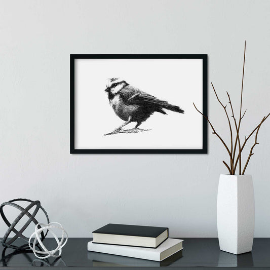 Bird drawing in a frame on a grey wall with vase and books below