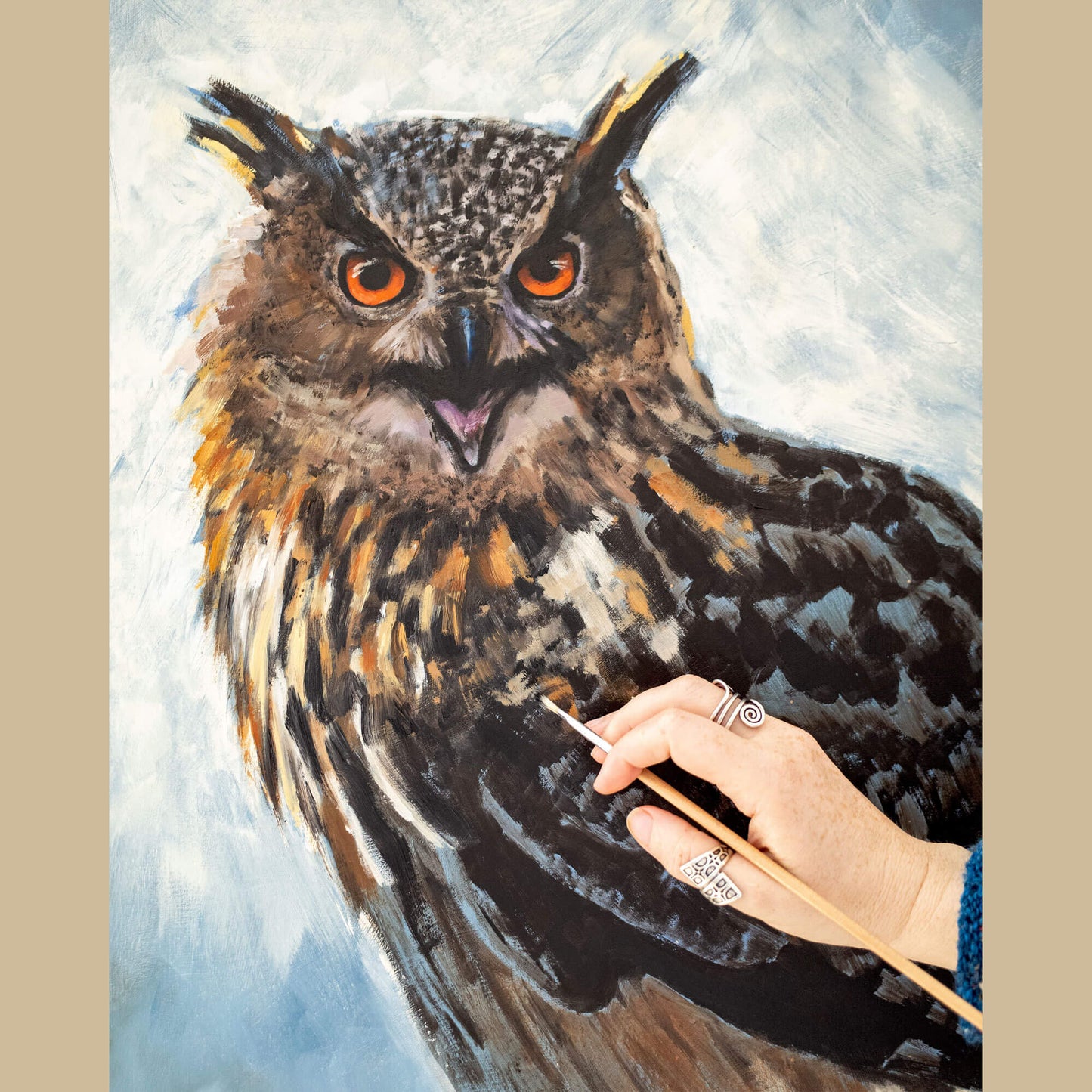Eagle owl oil painting in progress with artist's hand holding a brush, by bird artist Jill Dimond