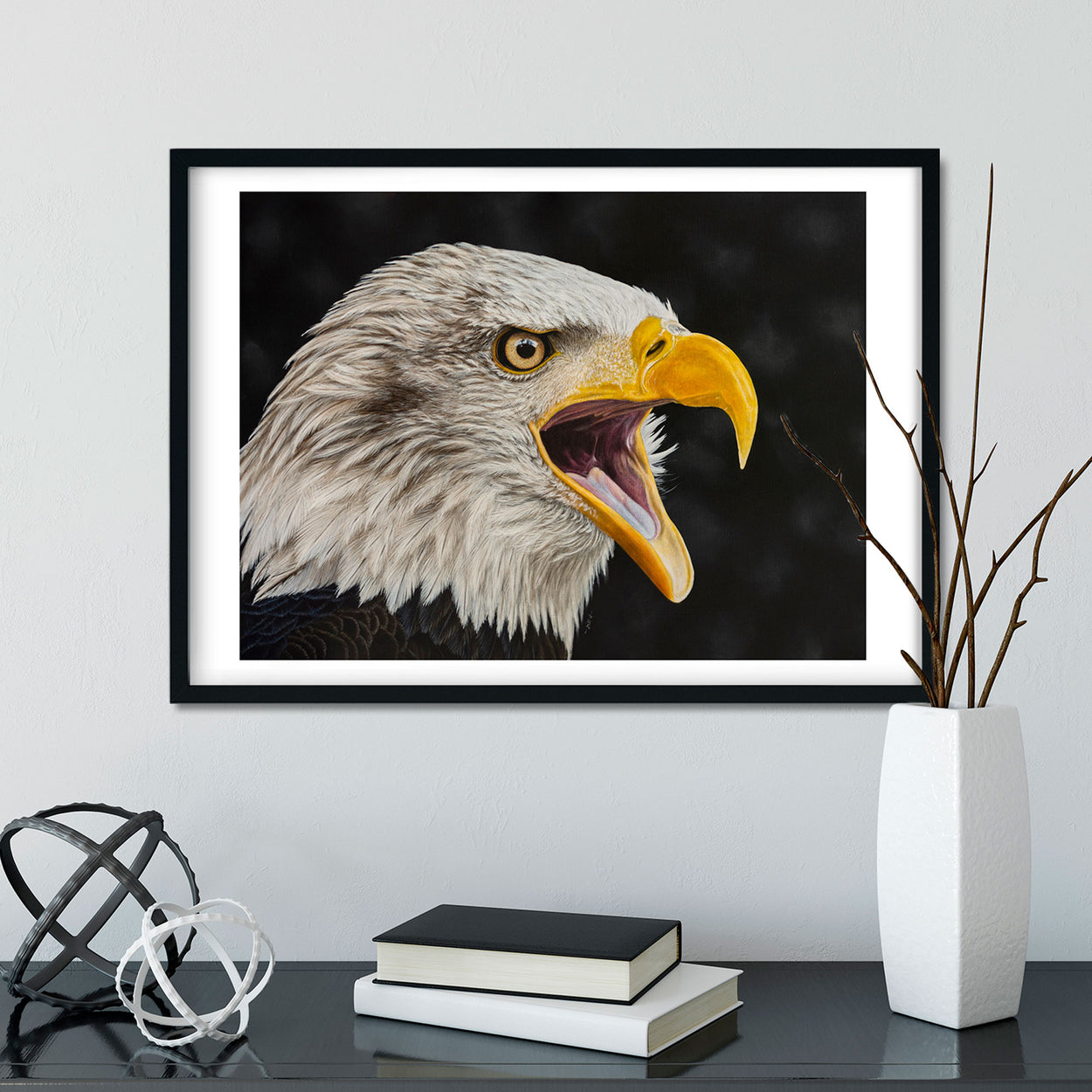 Black frame on white wall containing an art print of a bald eagle portrait with open beak
