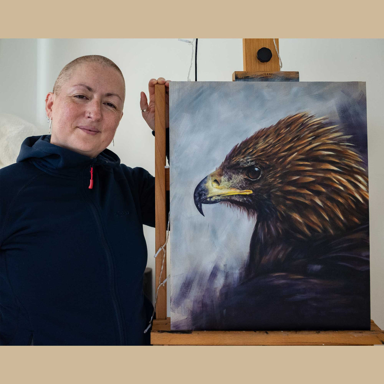 Golden eagle portrait on an easel with the artist, Jill Dimond, stood next to the painting