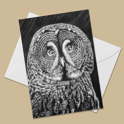 Greeting card with the image of a black and white drawing of a great greay owl looking straight at the viewer.  The card is on top of a white envelope.