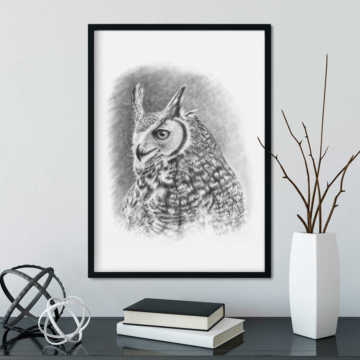 Black frame on wall containing black and white drawing of a great horned owl