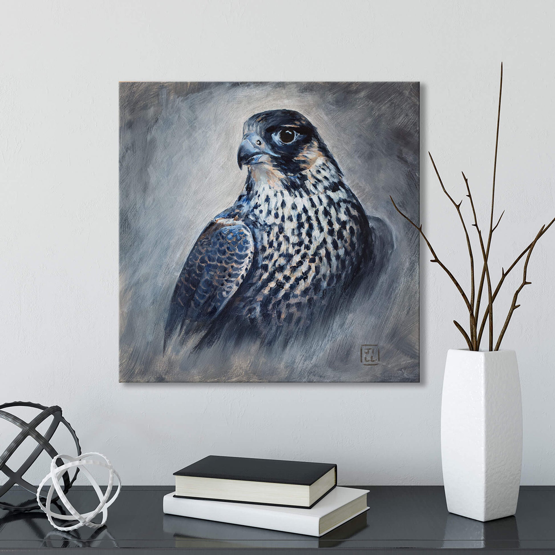 Painting of a peregine falcon on a wall above a table with books and decorative items.